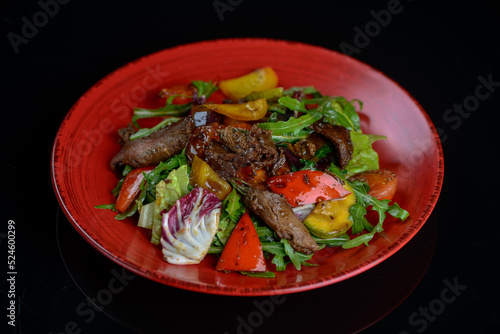warm salad with veal in a red plate 