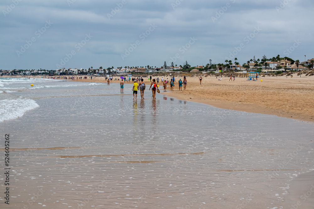 Obraz premium people walking along the seashore, early in the morning, at La Barrosa beach in Sancti Petri, Cadiz, Spain