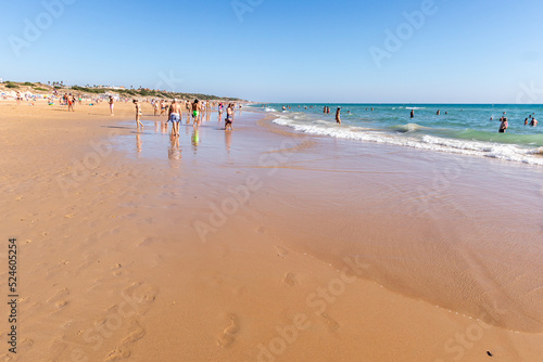 people walking along the seashore, early in the morning, at La Barrosa beach in Sancti Petri, Cadiz, Spain