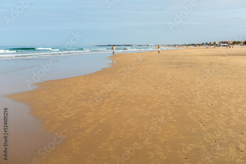 people walking along the seashore  early in the morning  at La Barrosa beach in Sancti Petri  Cadiz  Spain