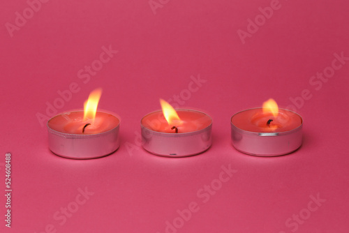 Flaming scented tea candles on pink background
