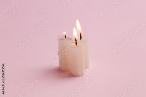 Three flaming candles on a pink background