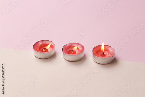 Flaming aroma candles on pink beige background. Top view