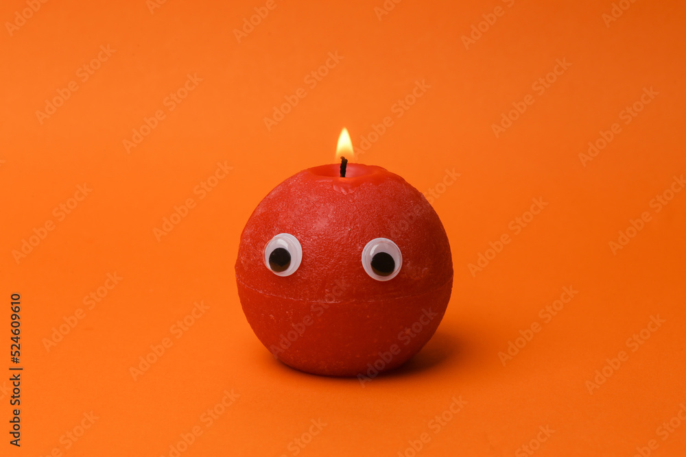 Flaming candle with eyes on orange background Flaming candle with eyes on orange background