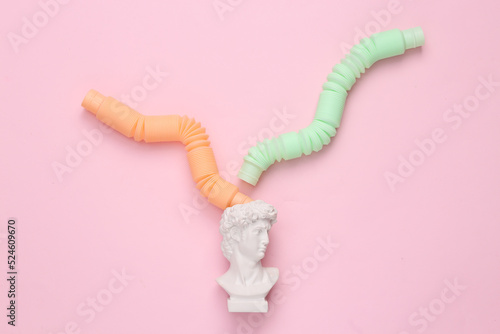 Bust David with antistress pop tube toy on pink background. Creative layout