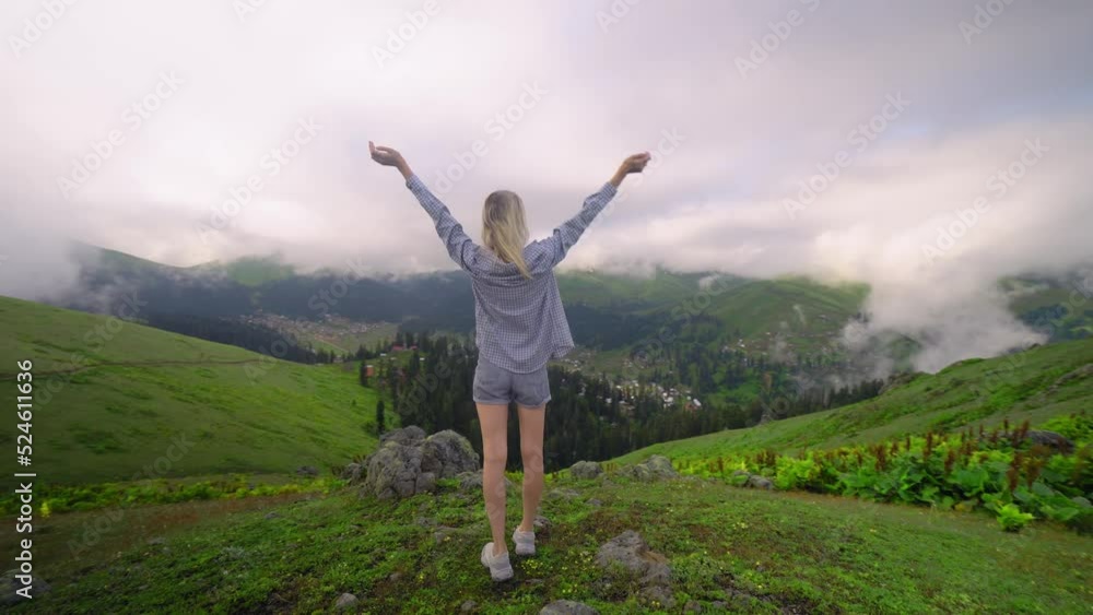 Young girl raised her hands up against background of clouds in high-altitude village in Georgian region of Bakhmaro. She is happy, beautiful view of sky and clouds. Delight overwhelms Young girl raised her hands up against background of clouds in high-altitude village in Georgian region of Bakhmaro. She is happy, beautiful view of sky and clouds. Delight overwhelms