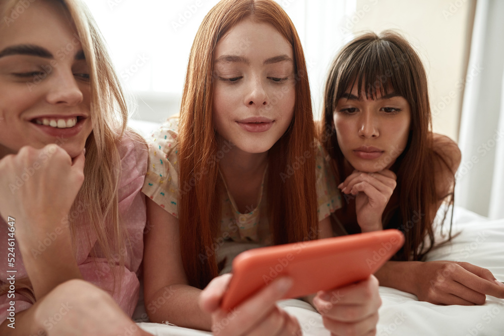 Girlfriends watching mobile phone in hand of girl Girlfriends watching mobile phone in hand of girl