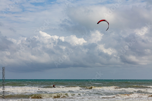 Professional kiter makes the difficult trick on a beautiful background. Kitesurfing Kiteboarding action photos man among waves quickly goes