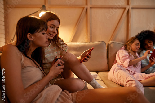 Young girls watching smartphones on sofa st home