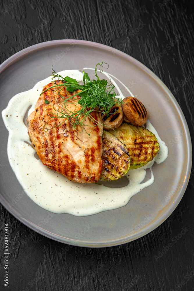 Chicken steak with vegetables in a ceramic plate on a dark textured background. Restaurant menu Isolated on black Chicken steak with vegetables in a ceramic plate on a dark textured background. Restaurant menu Isolated on black