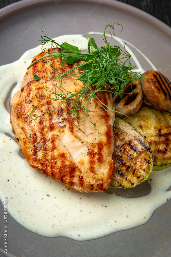 Chicken steak with vegetables in a ceramic plate on a dark textured background. Restaurant menu Isolated on black Chicken steak with vegetables in a ceramic plate on a dark textured background. Restaurant menu Isolated on black