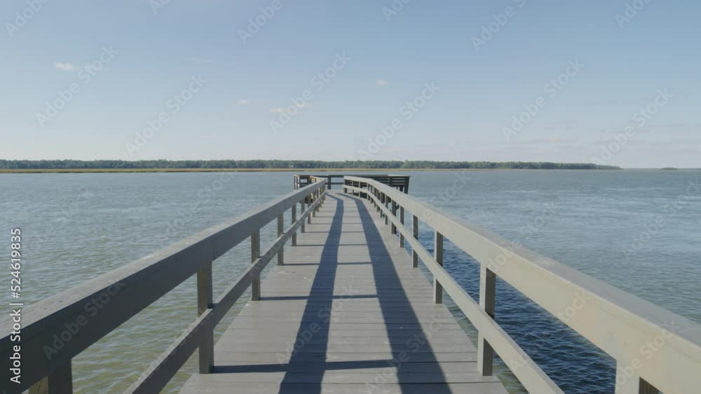 Slow motion through long wooden pier in brackish water bay in South Carolina in summer Slow motion through long wooden pier in brackish water bay in South Carolina in summer