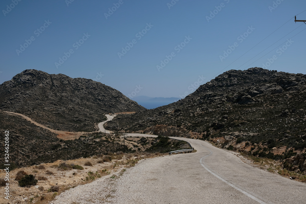 View of an empty road between mountains leading to the beach in Ios Greece