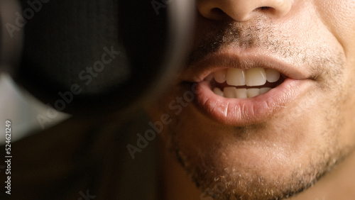 Close up on radio or podcast presenters mouth as he talks into a microphone  photo