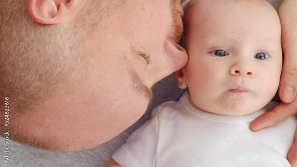 Happy newborn baby with his dad. Healthy newborn baby in a white t-shirt with father. Closeup Faces of the daddy and infant baby. Cute Infant boy and parent, top view. Slow motion. Happy family Happy newborn baby with his dad. Healthy newborn baby in a white t-shirt with father. Closeup Faces of the daddy and infant baby. Cute Infant boy and parent, top view. Slow motion. Happy family