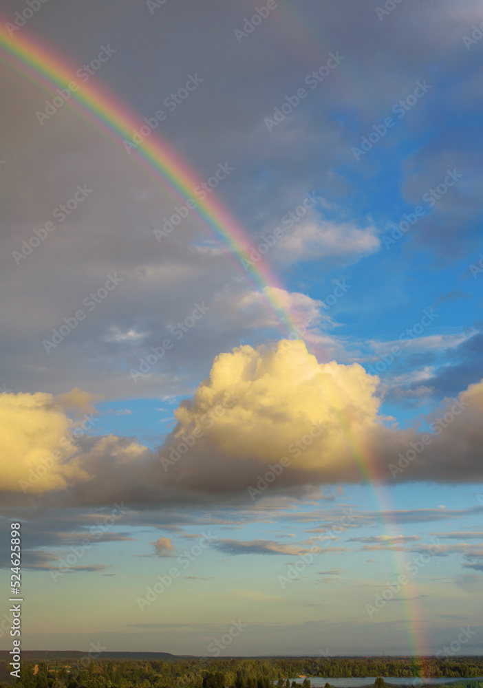 Real double rainbow in cloudy sky after rain. Afternoon. Weather forecast and climate change concept.