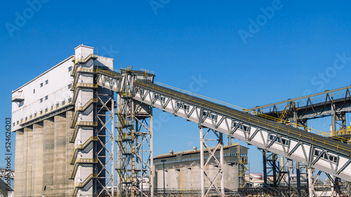 Conveyor gallery at the oil refinery. Installation of coke shipment at a petrochemical plant. Silo shipment unit. Production of deep oil refining. Technological buildings at the factory.