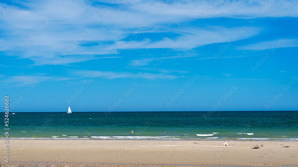 Panoramic view of beach with sailing yacht in ocean sailing and sky in background