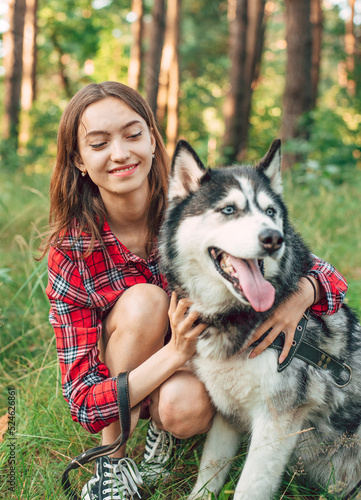 teenage girl playing and having fun with her siberian husky dog. Girl with dog in the forest © kurapatka