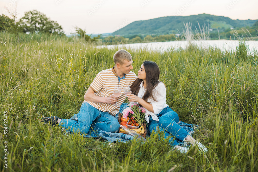 young happy couple having picnic outdoors in the countryside during beautiful sunset. Romantic date near the lake young happy couple having picnic outdoors in the countryside during beautiful sunset. Romantic date near the lake