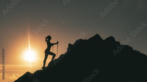 Woman climbs among rocks in a colorful mountain sunset