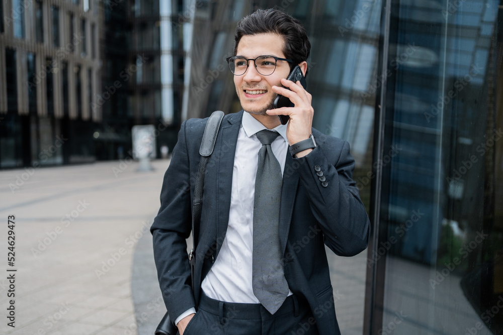 A male manager talks on a telephone in a business suit goes to work in the office with a briefcase A male manager talks on a telephone in a business suit goes to work in the office with a briefcase