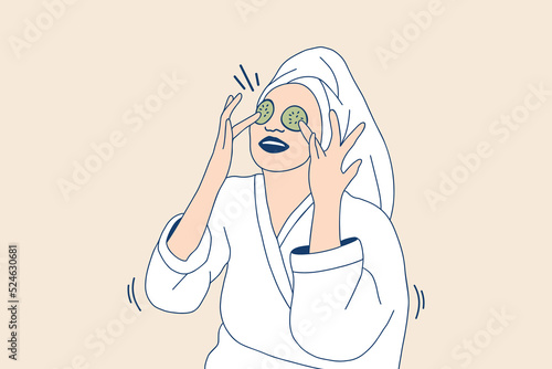 Illustrations Beautiful young woman in bathrobe applying a natural facial mask cucumber slices on face 