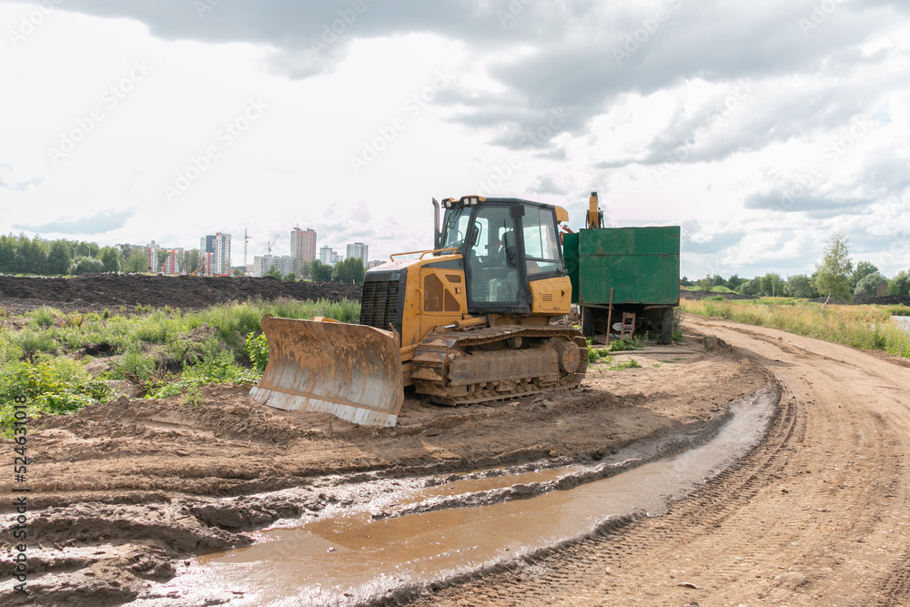Crawler bulldozer clears the ground with a metal shield. Landscaping. Road construction works. Crawler bulldozer clears the ground with a metal shield. Landscaping. Road construction works.