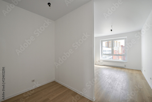 Empty room after repairs in an apartment building. Standard, stereotype fresh renovated room with wooden floor