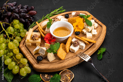 Dish of assorted tupes of cheese with honey on wooden background