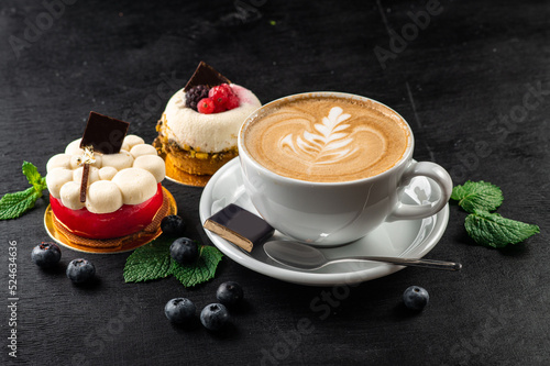 Cup of capuccino and cupcakes on wooden background