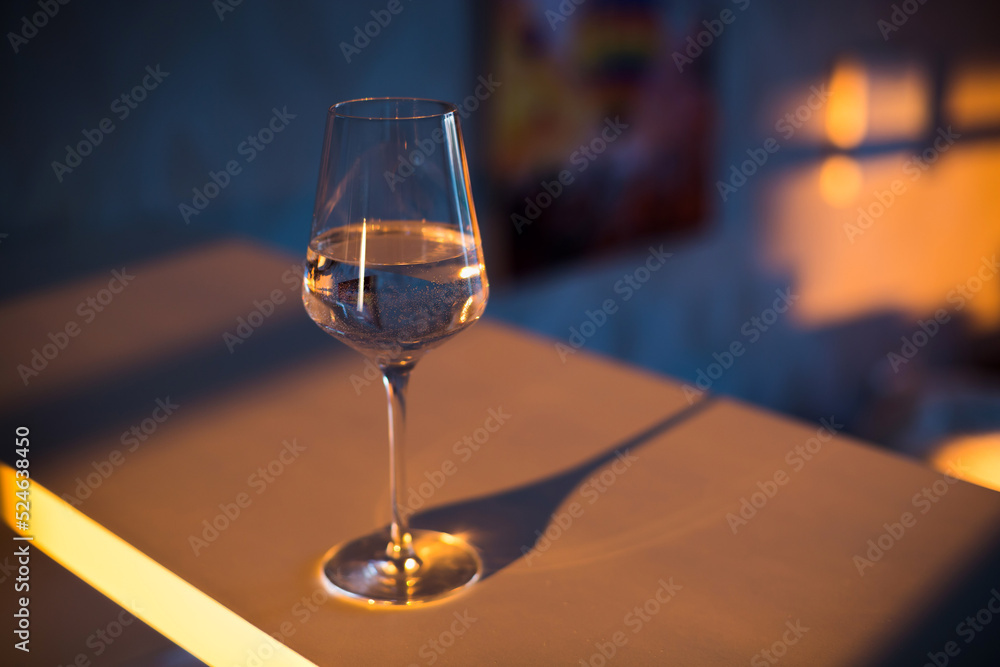 Obraz premium A glass of wine, water, lights up, glares against the background of the setting sun. Sunset in a glass.