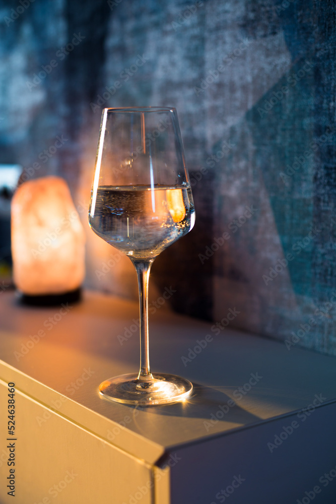 Obraz premium A glass of wine, water, lights up, glares against the background of the setting sun. Sunset in a glass.