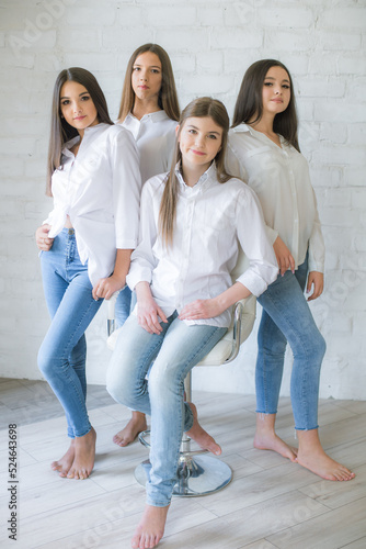 Pretty teenage girls models in trendy jeans and white shirts in the studio against the background of a white brick wall. Teenage fashion. beauty and fashion