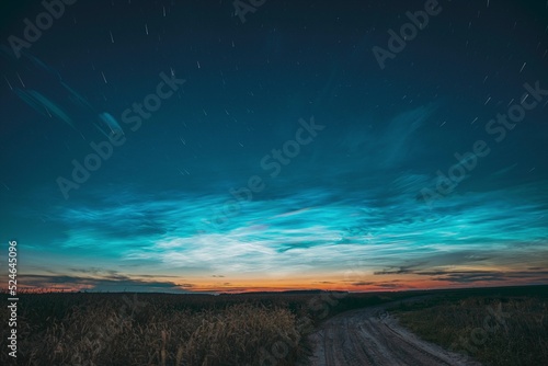 Amazing Rotate Stars Effect In Sky. Soft Colors. 6k Unusual Cloud And Stars Effects Above Countryside Rural Field Landscape With Young Wheat Sprouts. Night Blue Sky. , .