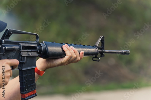 Hands aiming submachine gun. Firearms training. Target practice at firing range. Blurred background horizontal. High quality photo