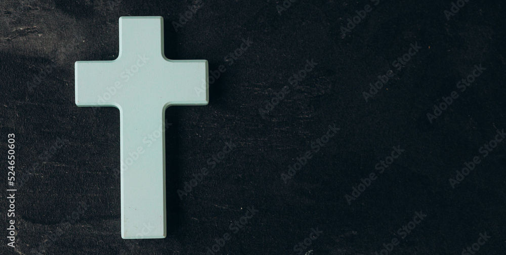 Christian cross on a textured black background. Religion concept. Blue cross