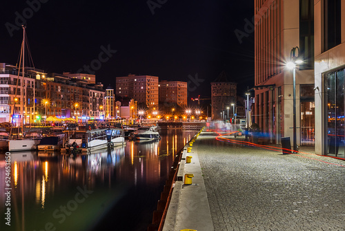 Night illumination of the embankment of the old town in Gdansk, reflections of the embankment lanterns on the surface of the water, tourist attractions in Poland © Александр Бочкала