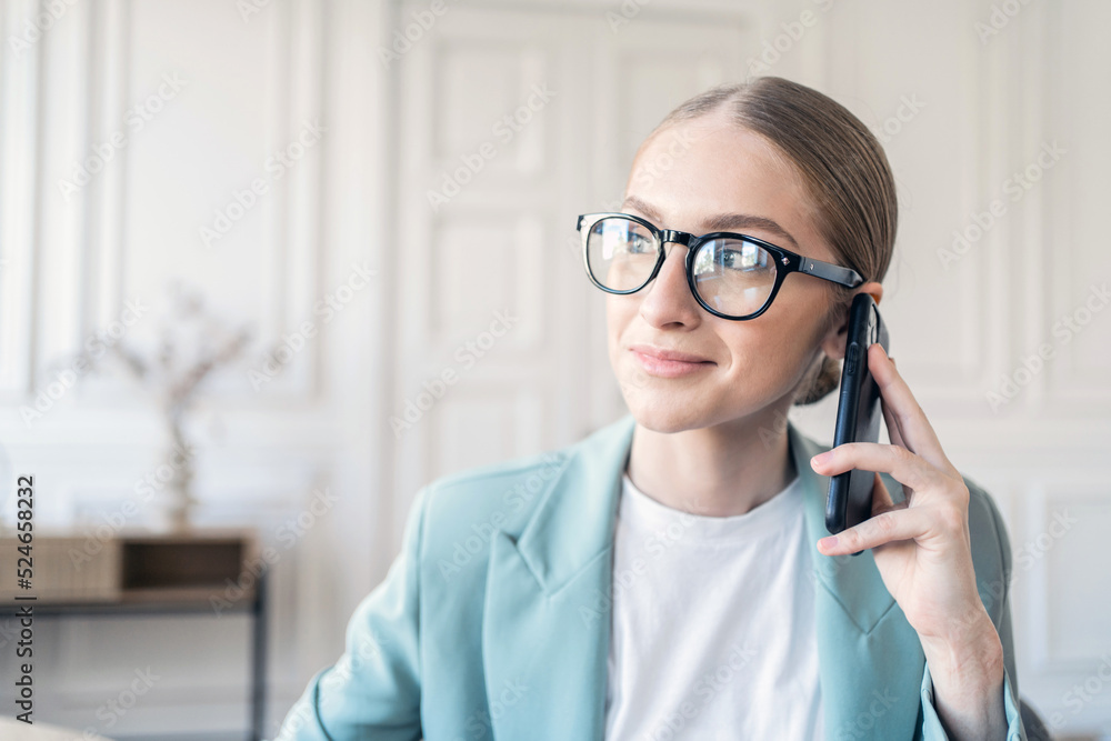 Portrait of a freelancer a woman with glasses working in an office talking on the phone Portrait of a freelancer a woman with glasses working in an office talking on the phone