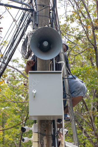 A man performs maintenance on a pole with a megaphone