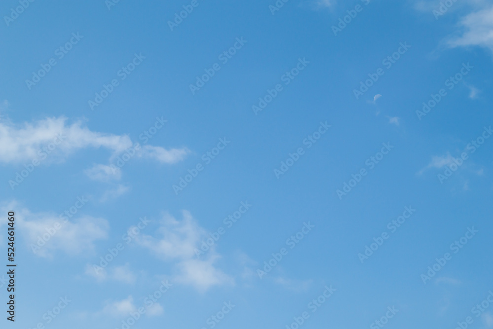Blue sky background and white clouds soft focus, pastel sky. The moon is high in the sky. Blue sky background and white clouds soft focus, pastel sky. The moon is high in the sky.