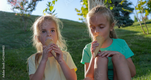 Two pretty little girls eating ice cream outdoor