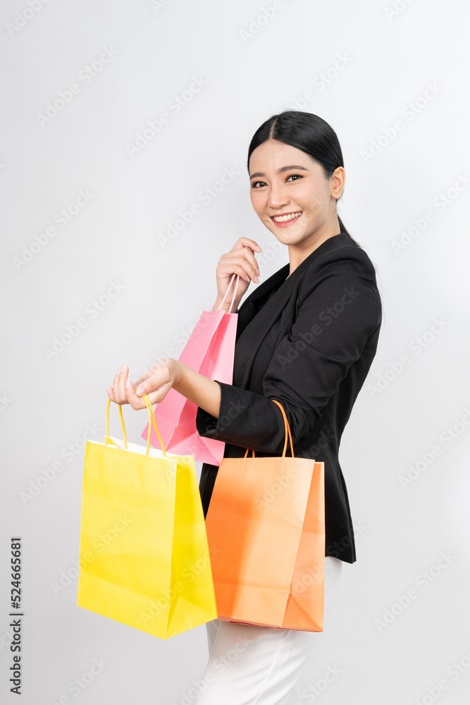 Photo of a young beautiful and elegant asian businesswoman wearing business suit and holding colorful shopping bags with a good nice friendly smile with different poses and emotion