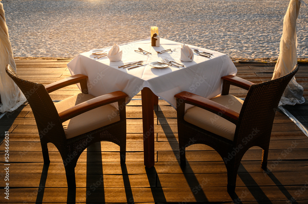 Romantic Dinner table and chairs on sand beach at sunset