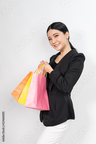 Photo of a young beautiful and elegant asian businesswoman wearing business suit and holding colorful shopping bags with a good nice friendly smile with different poses and emotion