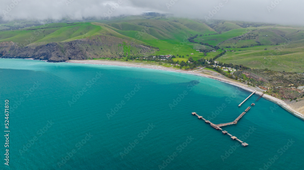 an areal view for the Rapid Bay Jetty and the green surroundings while the clouds are very low and covering the top of the hills. The jetty is a popular location for scuba divers.