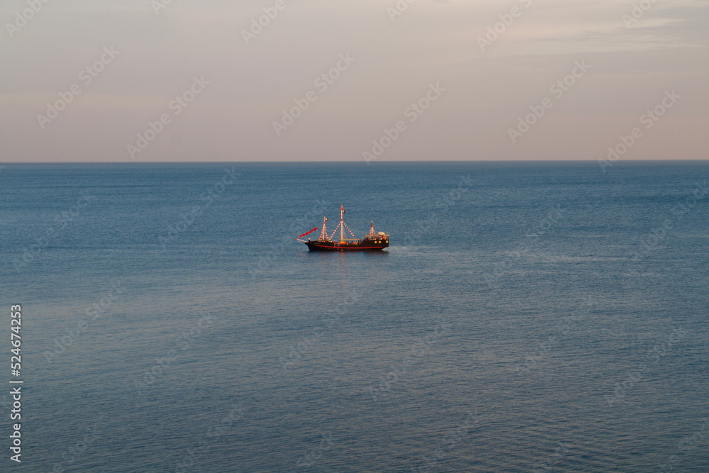 A small ship in the middle of a calm blue sea. A small ship in the middle of a calm blue sea.