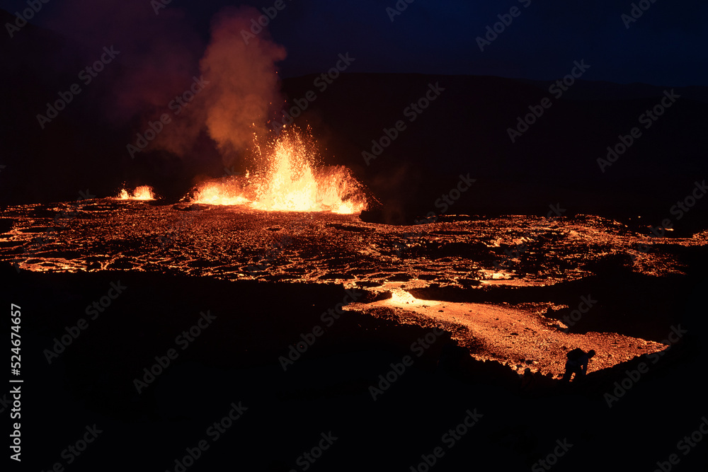 Volcano eruption at Meradalir near Fagradalsfjall, Iceland. Silhouette of a man on a flowing lava background.