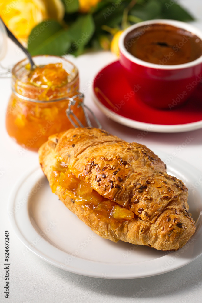 Croissant with orange jam on a white plate Croissant with orange jam on a white plate