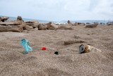 Garbage on a beach left by holiday-makers, environmental pollution concept picture. Sand, sea, sky and recycle trash. Harm to ecology, environmental damage. Convert waste into reusable material.